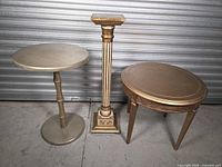 Three gold-finished wood tables and pedestal grouped