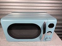 Front view of aqua Galanz countertop microwave showing chrome handle and controls