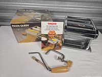Pasta machine with clamp, crank, brush, booklet and box displayed