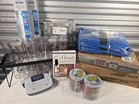 Group shot showing all items including label maker, Flex Tape, garment rack boxes, exit sign box, blue tarp bags, tie caddies, shelf liner