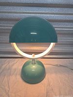 Front view of teal and white metal table lamp, shade closed