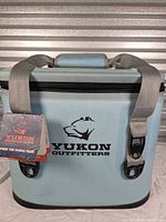 Front view of Yukon Outfitters light blue soft-sided cooler with tags attached