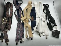 All eight pairs of suspenders and fabric pouch laid flat showing colors, clips, junctions