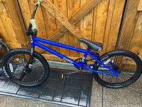 Full left side view of blue Capix BMX bike leaning against wooden fence