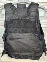 front view of black tactical vest showing Velcro fields and pocket flaps