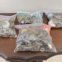 Three bags of assorted furniture hardware on table