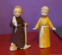 Front view of both monk figurines showing poses, coloration and accessories