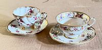 Two complete cup and saucer sets side by side