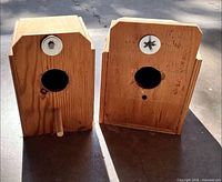 Front view of both wooden bird boxes showing entrance holes, perch, mounting bolts