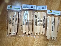 Four sealed packages of 8” wooden plant markers showing printed names