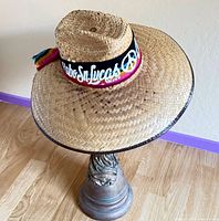 Top and side view of straw sombrero on stand showing embroidered band and brim