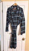 Full view of teal plaid flannel robe on hanger showing length, sleeves and belt