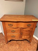 Front view showing serpentine front, drawers, cabinet door, brass pulls.