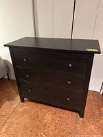 Front view of black three-drawer dresser