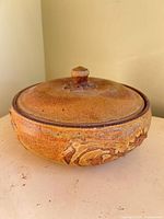 Side view of lidded stoneware casserole showing exterior glaze and knobbed lid