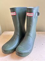 Full view of both green Hunter rain boots front and side