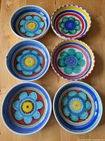 Top view of six hand-painted ceramic bowls showing floral designs and colour palette