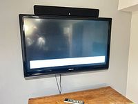 Front view of wall-mounted Toshiba TV with soundbar on top and remote below