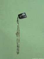 Full view of gold-tone chain bracelet with tag and clasp visible