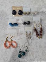 Overall view of nine pairs of earrings arranged on display cards