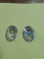Both oval glass/crystal gemstones side by side showing front facets