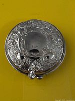 top view of ornate silver-plated compact on yellow background