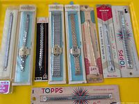 Overall view of nine packaged watch bands on yellow background