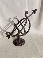 Front angle of cast iron armillary sphere showing rings, arrow, base