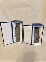 Front view of both figurines inside boxes