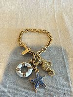 Full view of bracelet showing chain, toggle clasp, Coach tag and three charms