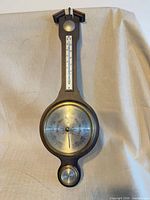 Full view of wooden wall barometer showing thermometer, barometer, hygrometer