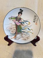 Front view of porcelain plate on stand displaying Asian woman motif and cloud design