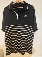 Front view of Skechers black and white striped polo shirt on hanger