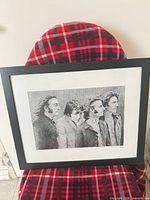 Full view of framed print on plaid background shows overall appearance and frame color