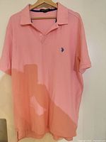 Front view of pink polo shirt on hanger