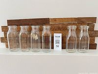 Front view of six clear glass milk bottles aligned