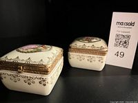 Two identical porcelain trinket boxes side by side showing size and design