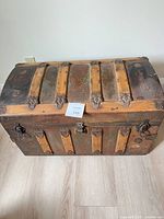 Front and top view of dome top trunk showing wood panels, iron slats, hardware and general wear