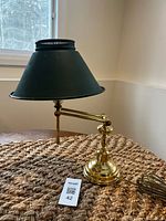 Full view of brass desk lamp with green shade on table