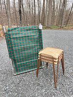 Camp cot folded beside stacked stools