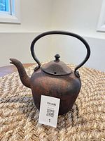 Front view of rusted cast iron kettle on mat
