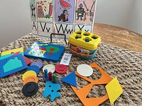 Overall lot showing alphabet mats, Fisher-Price shape sorter, puzzle board, foam shapes, discs and pegs