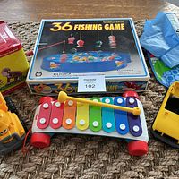 Boxed 36 Fishing Game, Curious George musical tin, Fisher-Price xylophone, yellow dump truck front section, MaxSold lot tag