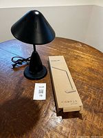 Boxed LED desk lamp next to black lamp on table