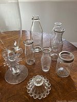 Group shot of all glass pieces on table: vase, bottles, jars, candle holders