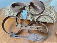 Collection of rusted barrel hoops and two strap-on skates on woven mat