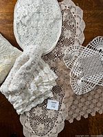 Stack of crocheted and lace linens showing variety of pieces