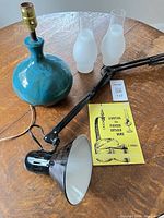Group shot of ceramic lamp, swing-arm lamp, two chimneys and reference ruler