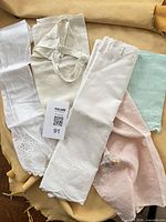 Group of five linens showing aprons, curtain, doily, towel with lot tag