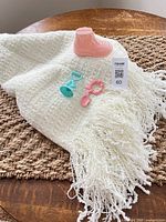 Throw blanket with fringe, boot bank, pacifier and rattle displayed